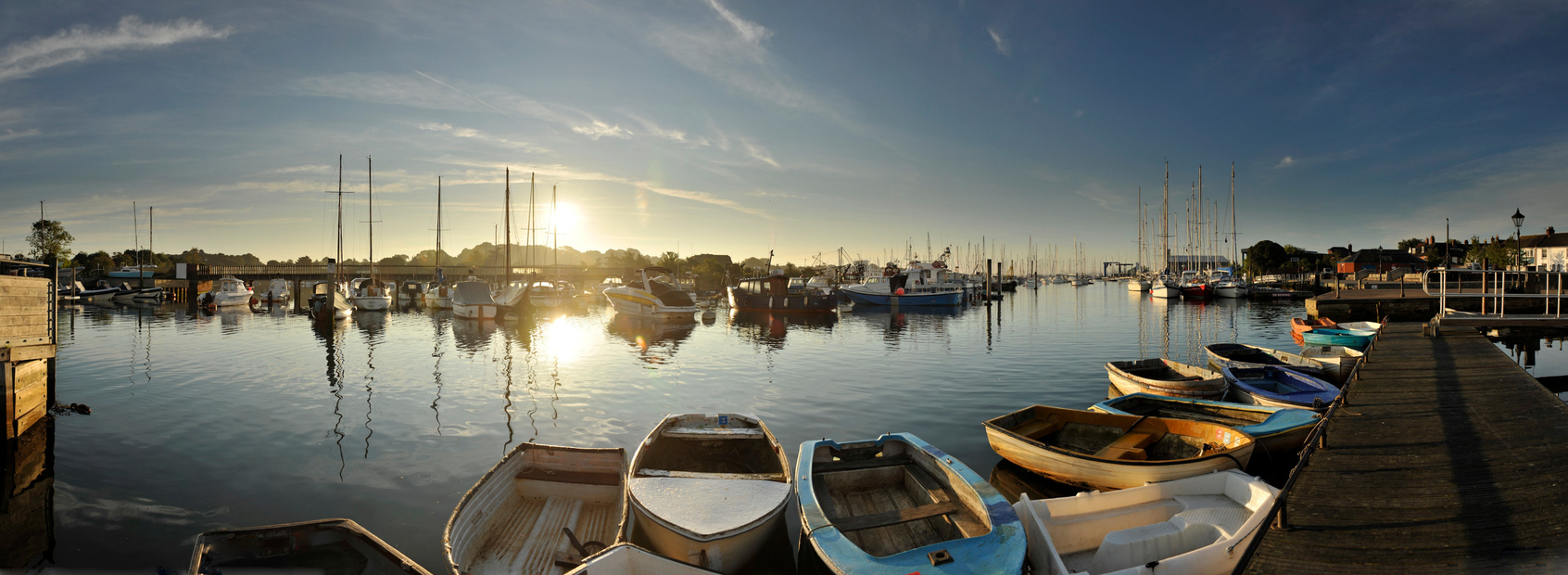 A panoramic image of Lymington Harbour in Hampshire England taken at dawn with the sun just above the horizon, taken on a bright summers day