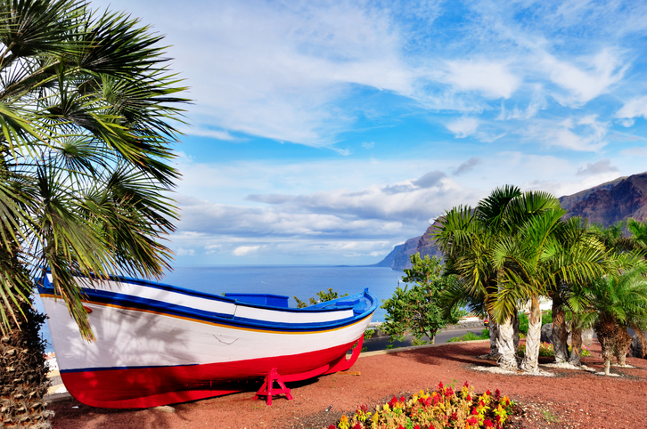 A colourful painted fishing boat on display near the ocean in Los Gigantes, Tenerife, Canary Islands, a picture postcard scenic view of the island.